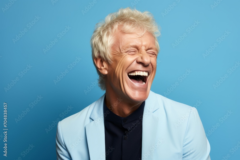 Portrait of a senior man laughing against blue background. Human emotions and facial expressions concept. Portrait of a senior man laughing against blue background. Human emotions and facial expressions concept.