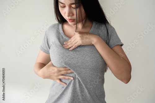 Young Asian woman pressing touching her chest for checking lady breast cancer symptom diagnosis breast self exam(BSE). Woman health inspect cancer awareness concept. photo