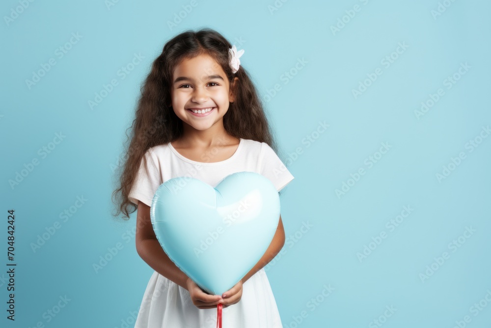 Cute African American girl holding heart shaped balloon on blue background Cute African American girl holding heart shaped balloon on blue background