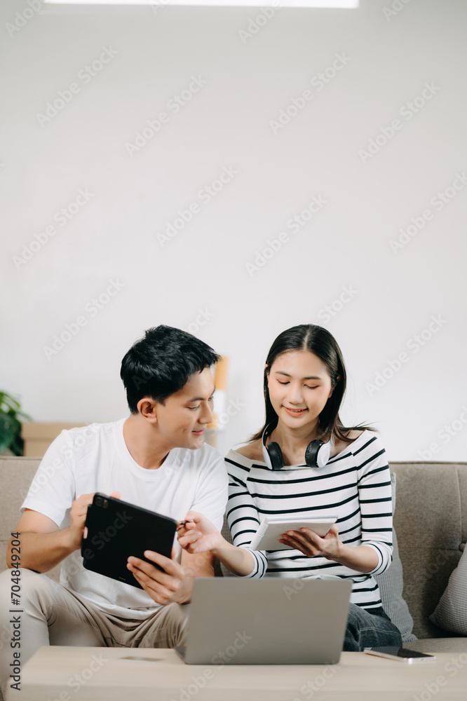 Female discussing new project with male colleague. Young woman talking with young Asian man with financial on sofa Female discussing new project with male colleague. Young woman talking with young Asian man with financial on sofa