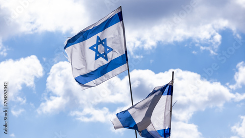 Two israeli flags waving on blue sky background