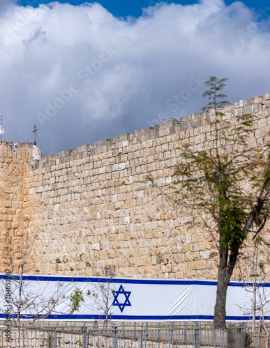 Large Israeli flag on Jerusalem's Old City Wall background © vadiml