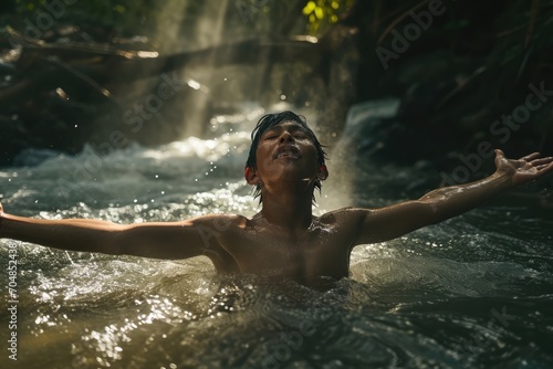 Handsome young man in worship in a river at sunset. Front view.  The beauty and power of Faith. Christian concept. © Faith Stock