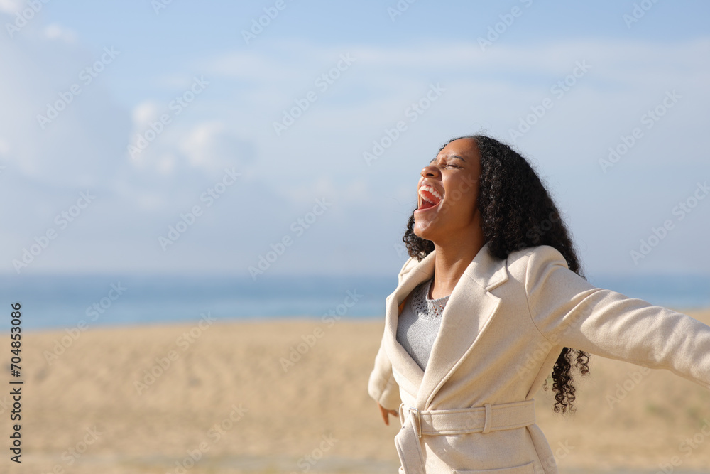 Happy black woman on the beach screaming in winter Happy black woman on the beach screaming in winter