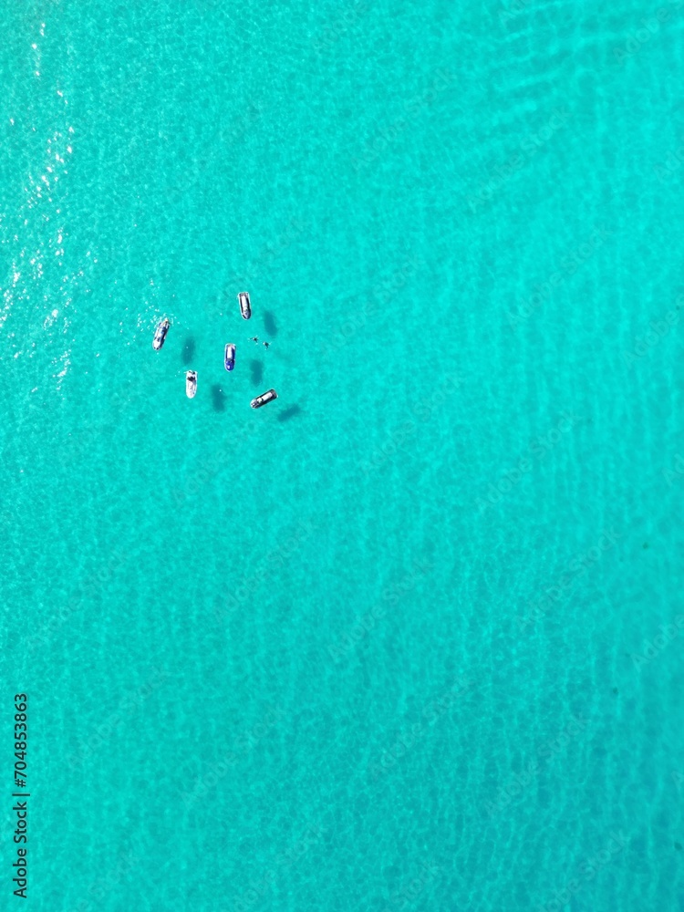 Fototapeta premium Peaceful scene of a cluster of boats drifting in the tranquil blue sea