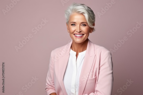 Portrait of smiling senior business woman with grey hair wearing pink suit