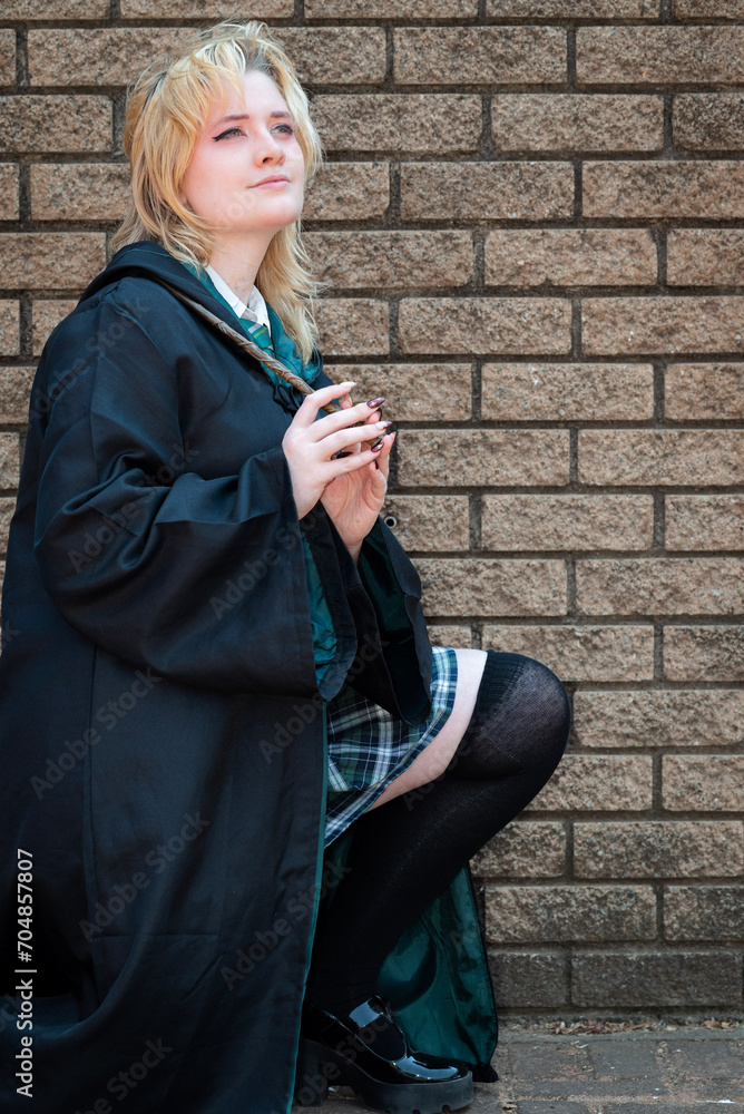 Blonde Caucasian female cosplayer dressed as a wizard with a magic wand