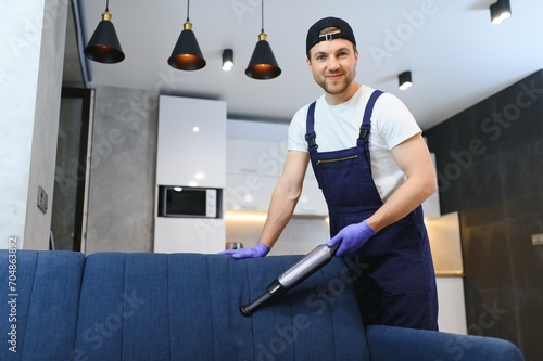 housekeeper holding modern washing vacuum cleaner and cleaning dirty sofa with stain with professionally detergent. Professional springclean at home concept photo