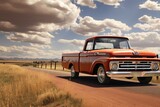 An orange truck drives down a dirt road, A pick-up truck on an open road in the American countryside, AI Generated
