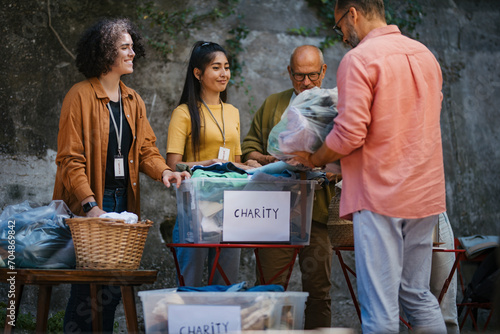 People sorting donated used clothes for charity photo