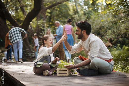 Young man and girl with herb crate highfiving at community garden photo