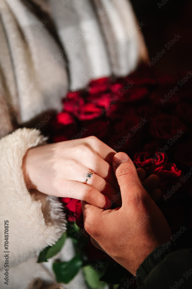 Marriage proposal. Will you marry me. She said yes. A couple hand with wedding ring on a bouquet of red roses. Love concept. Elegant floral template for design for Valentine's Day. Engagement ring. Marriage proposal. Will you marry me. She said yes. A couple hand with wedding ring on a bouquet of red roses. Love concept. Elegant floral template for design for Valentine's Day. Engagement ring.