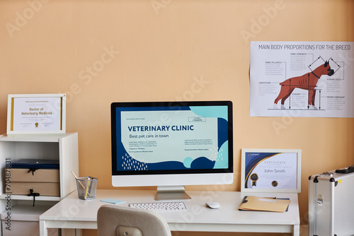 Computer on desk near certificates and dog diagram in veterinary clinic photo