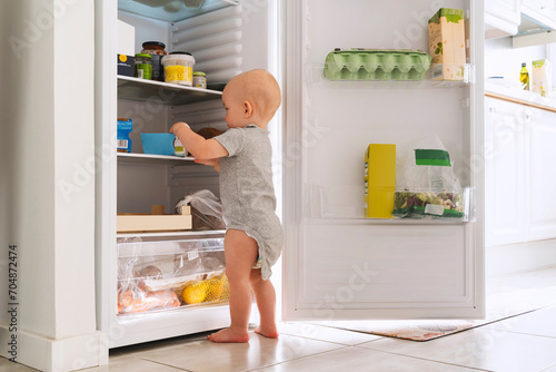 Baby boy exploring food in refrigerator at home photo
