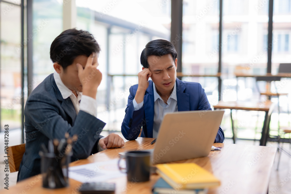 Two young asian businessmen stressed over failed investment with laptop computer. Two young asian businessmen stressed over failed investment with laptop computer.