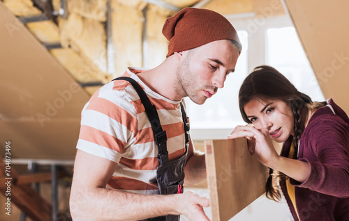 Couple measuring wooden plank at home photo