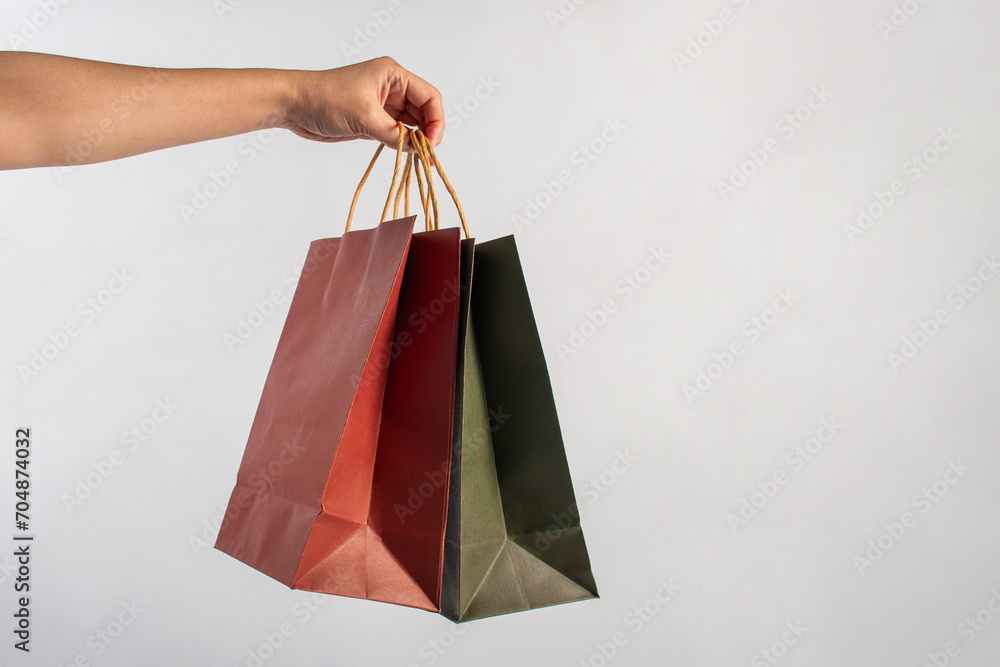 Red and green paper shopping bag in hand on white background.
