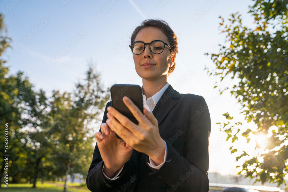 Businesswoman using smart phone in park under sky Businesswoman using smart phone in park under sky