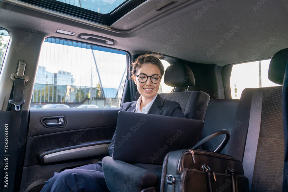 Smiling businesswoman using laptop in car Smiling businesswoman using laptop in car