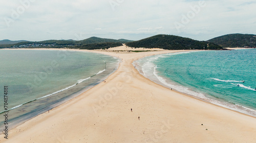 drone view of an Australian beach that joins an island and separates the sea in two