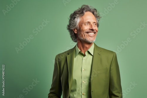 Handsome middle aged man in a green suit smiling at the camera.