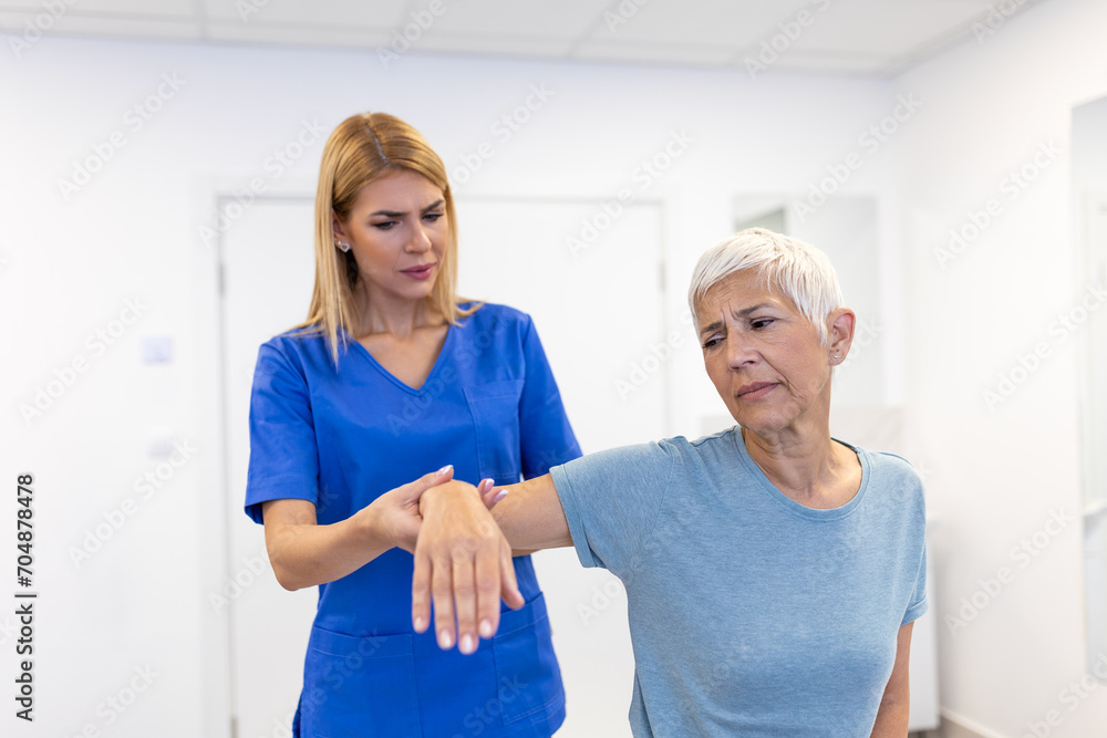 Fototapeta premium Doctor or Physiotherapist working examining treating injured arm of senior female patient, stretching and exercise, Doing the Rehabilitation therapy pain in clinic.