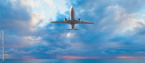 Airplane flying over stormy tropical sea at sunset