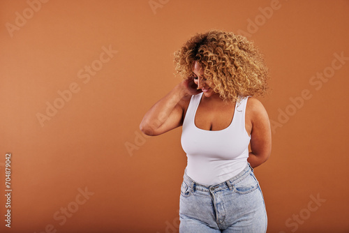 Laughing woman in a tank top and jeans posing on an orange background photo