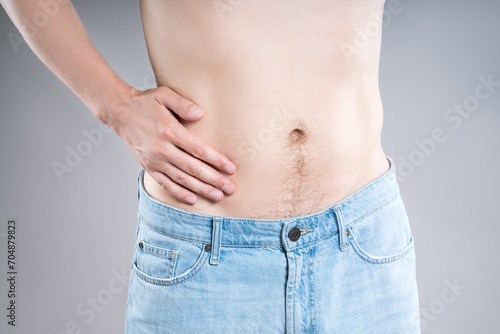 Inflammation of appendicitis, stomach ulcer, man with abdominal pain on a gray background, symptoms of gastritis, diseases of the digestive system © staras