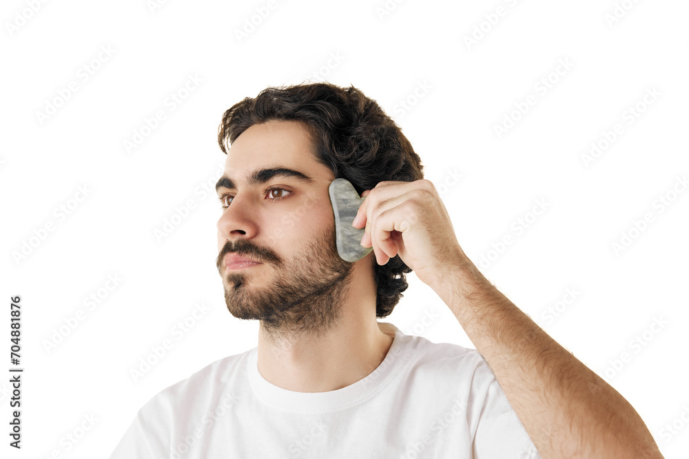Obraz premium Close up portrait of man moves smoothly over skin of his face with massage tool against white studio background. Concept of male facial care routine, cosmetic product, anti-aging treatment.