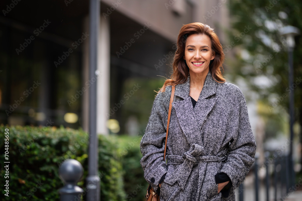 Brunette haired woman wearing tweend coat and walking outdoors in the city street on autumn day Brunette haired woman wearing tweend coat and walking outdoors in the city street on autumn day