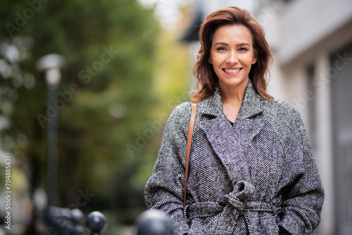 Brunette haired woman wearing tweend coat and walking outdoors in the city street on autumn day photo