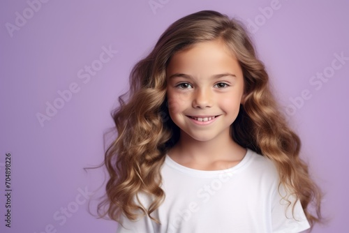 Portrait of a cute little girl with long curly hair on a purple background