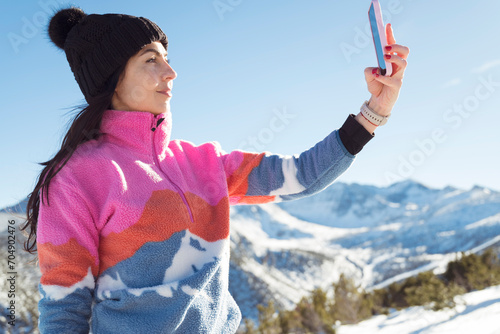 Beautiful Woman using mobile phone in the Winter Snowy Mountain .Woman making selfie 