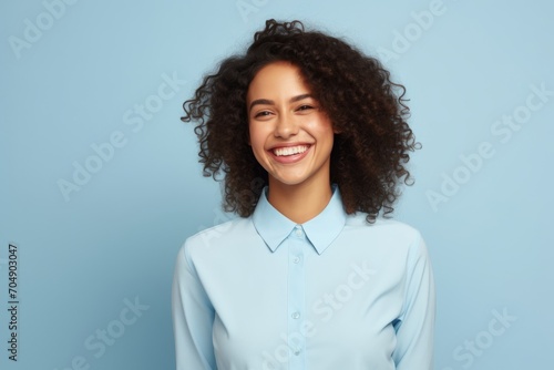 happy african american woman with curly hair and blue shirt on blue background