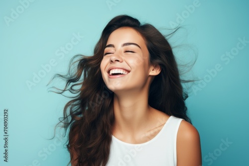 Portrait of young happy smiling woman with long hair over blue background