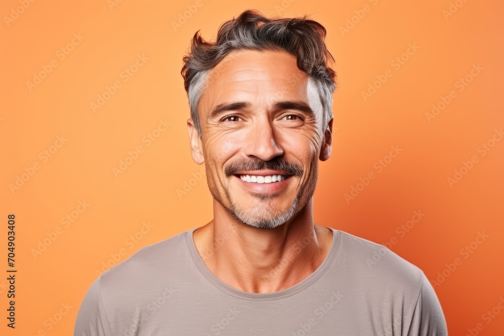 Portrait of a smiling mature man in grey t-shirt on orange background Portrait of a smiling mature man in grey t-shirt on orange background