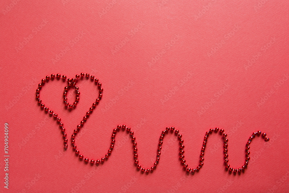 Heart shape with red ribbon made of beads on red background. Valentines day concept, empty card mockup