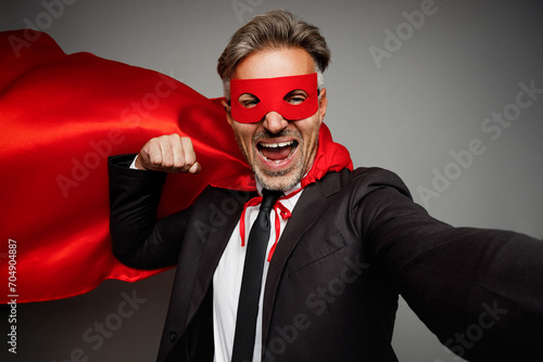 Adult cool employee business man corporate lawyer wear classic formal black suit shirt tie super hero red cloak work in office do selfie shot pov mobile cell phone isolated on plain grey background.