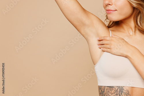 Close up cropped young nice lady woman with slim body perfect skin wear nude top bra lingerie standing raise up hand touch armpit isolated on plain pastel beige background. Lifestyle diet fit concept.