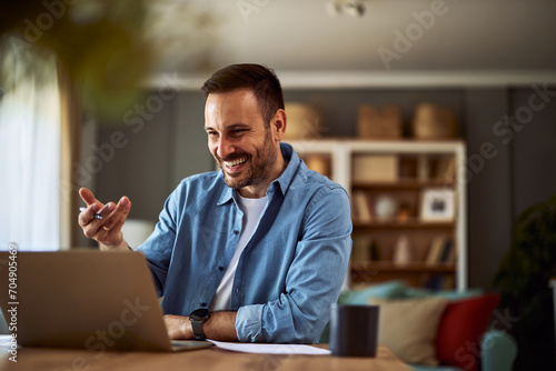 A cheerful adult male online teacher talking with his students on an online platform for his online class on his laptop.