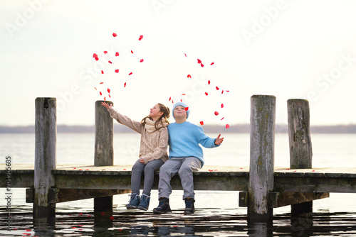 Kinder werfen rote Blüten in die Luft am See photo