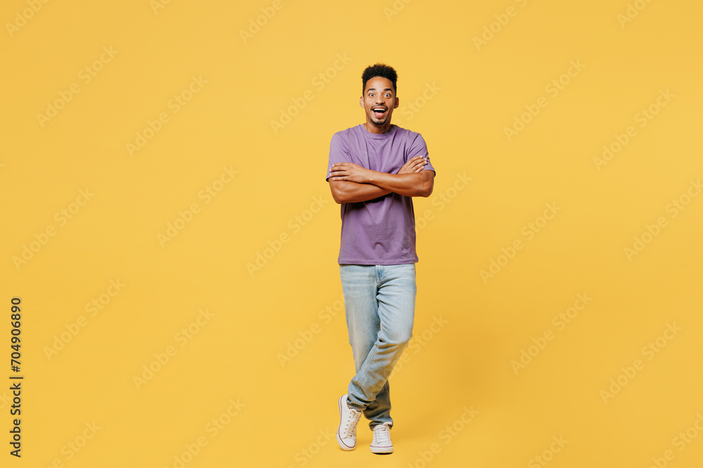 Fototapeta premium Full body young man of African American ethnicity he wears purple t-shirt casual clothes hold hands crossed folded look camera isolated on plain yellow background studio portrait. Lifestyle concept.