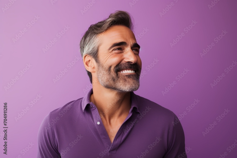 Portrait of handsome mature man looking at camera and smiling while standing against purple background Portrait of handsome mature man looking at camera and smiling while standing against purple background
