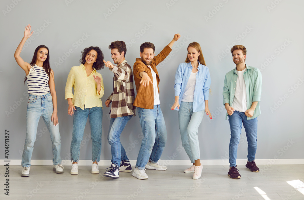Obraz premium Portrait of a group of young happy smiling friends students or colleagues in casual clothes standing together, looking positively at the camera and having fun on a grey background.