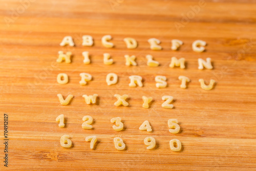 Raw alphabet pasta on cutting board, side view, selective focus