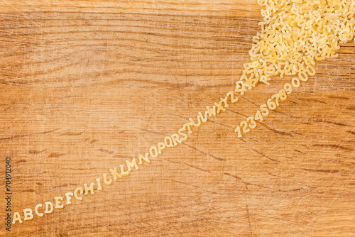 Raw alphabet pasta on cutting board lined up from heap