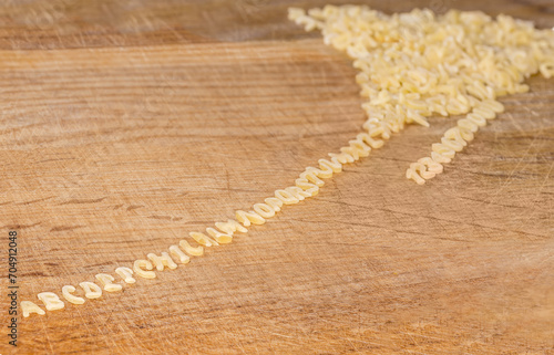 Raw alphabet pasta on cutting board lined up from heap