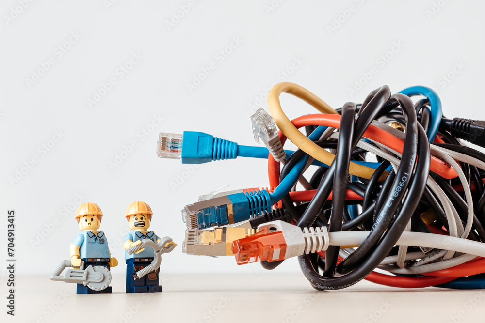 Fototapeta premium Confused technicians and a tangled bunch of network cables. Illustrative editorial. Illustrative editorial