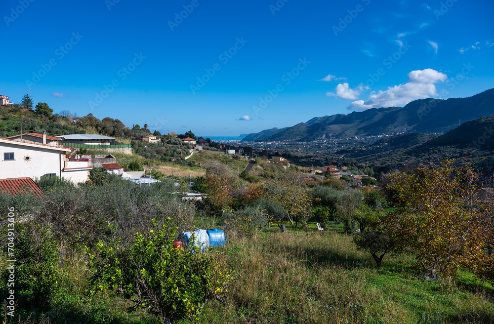 Panoramic view over the rough mountains with houses and blue sky around Monreale, Italy